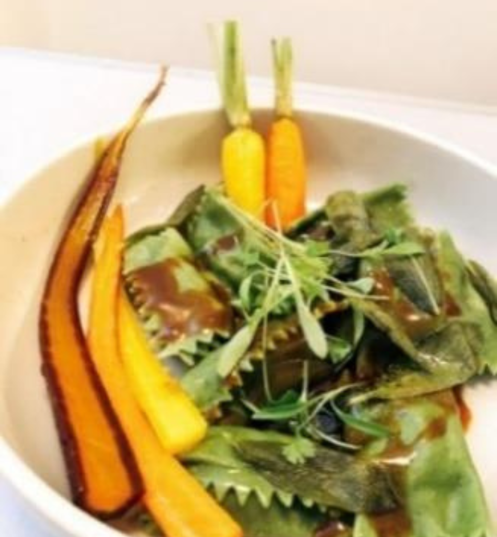 A bowl of food with carrots and greens.