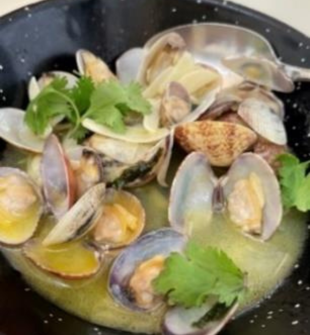 A bowl of clams with parsley in it.