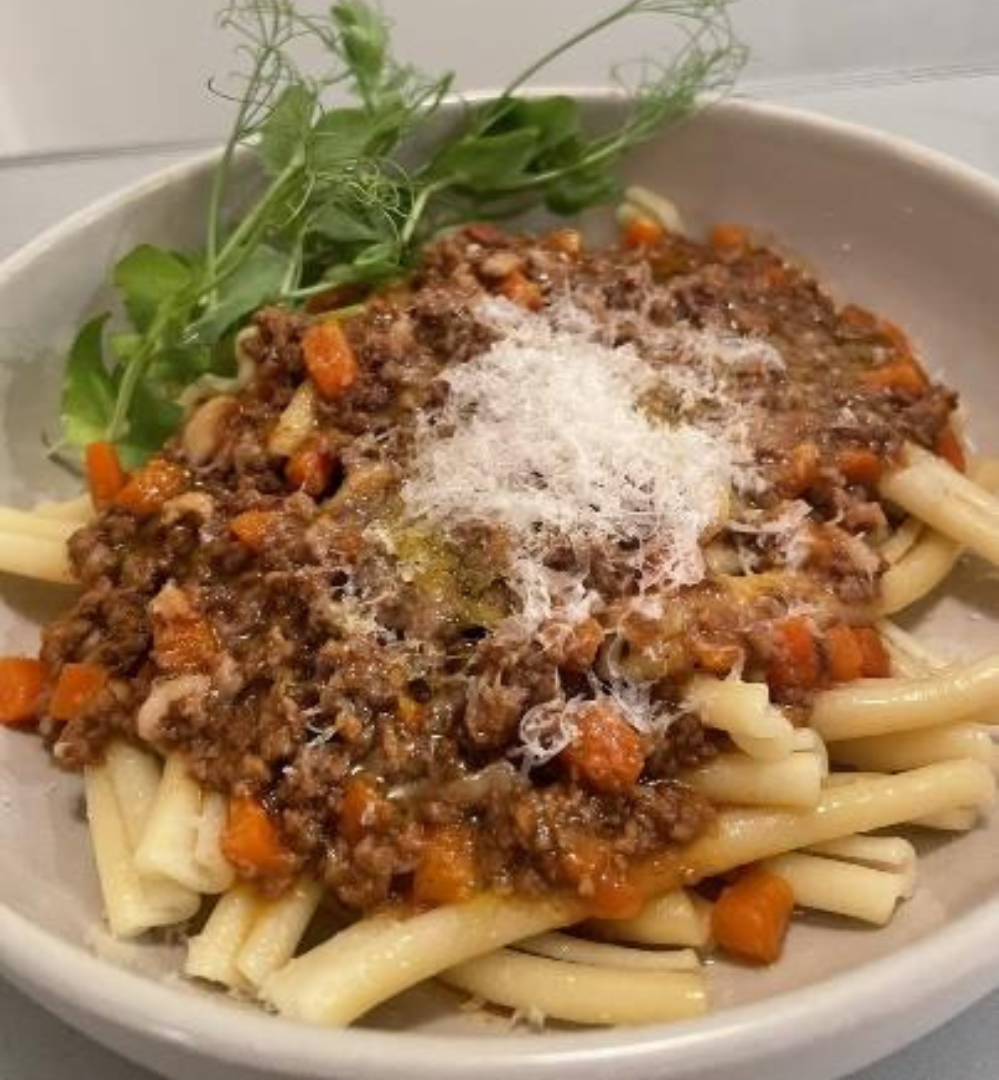 A bowl of pasta with meat and sauce.