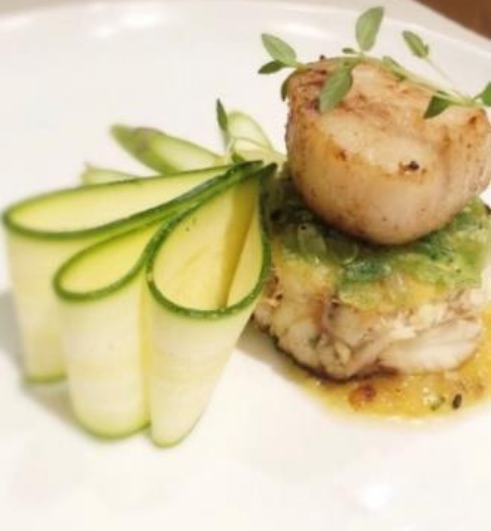 A plate of food with scallops and zucchini.