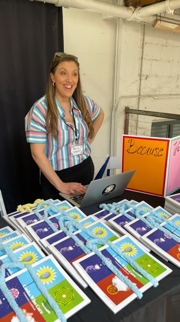 A woman standing next to a table with many books.